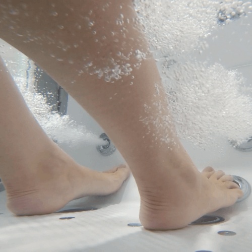 Underwater view of feet enjoying foot-level hydro massage jets