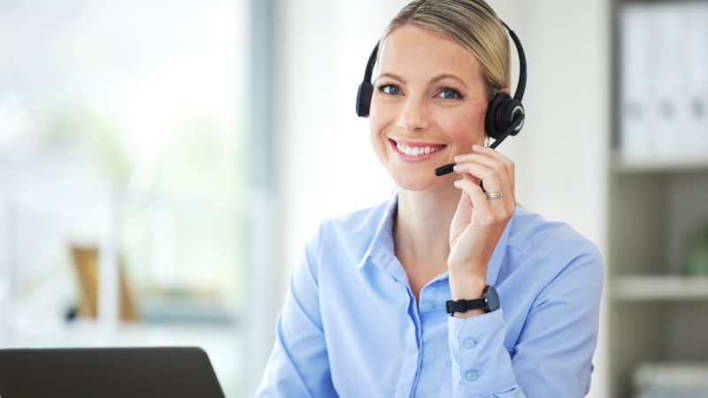 Friendly customer service agent wearing a headset smiling at desk